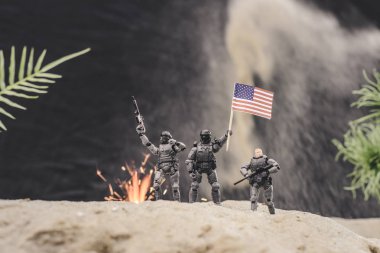 silah ve amerikan bayrağı kumul üzerinde patlama yakınında duran oyuncak askerlerin seçici odak 
