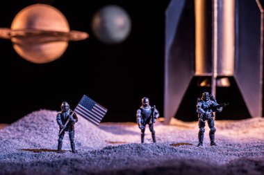 roket ve gezegenlerin yakınında uzayda Amerikan bayrağı tutan oyuncak askerler