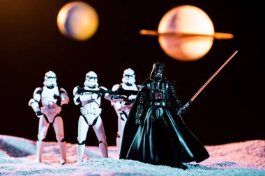white imperial stormtroopers with guns and Darth Vader with lightsaber with planets on background