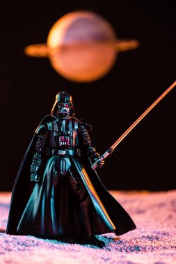 Darth Vader figurine with lightsaber with planet on background