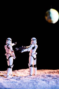 white imperial stormtrooper aiming with gun at another on black background with planet Earth