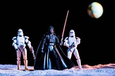 two white imperial stormtroopers with guns and Darth Vader with lightsaber with planet Earth on background