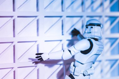 plastic Imperial Stormtrooper climbing white textured wall