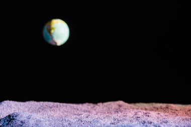 sandy ground with blurred planet Earth in space isolated on black with copy space clipart