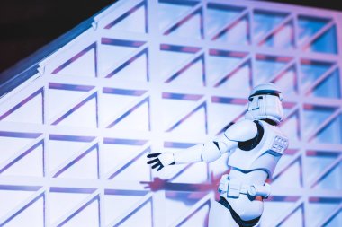 plastic Imperial Stormtrooper climbing white textured wall isolated on black