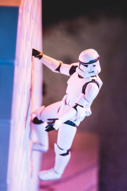 white toy Imperial Stormtrooper climbing white textured wall