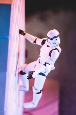 white toy Imperial Stormtrooper climbing white textured wall clipart