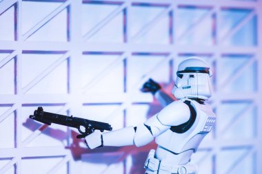 white plastic Imperial Stormtrooper climbing with gun on white textured wall