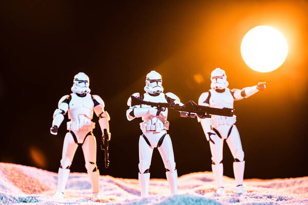 KYIV, UKRAINE - MAY 25, 2019: white imperial stormtroopers with guns on cosmic planet with sun on background