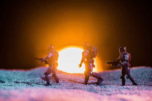 toy soldiers silhouettes with guns walking on planet with sun on background