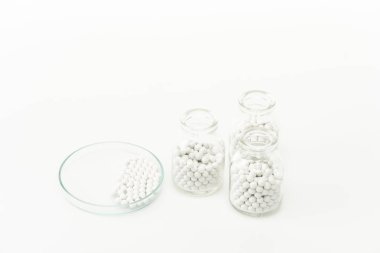 bottles with pills near glass plate isolated on white  clipart