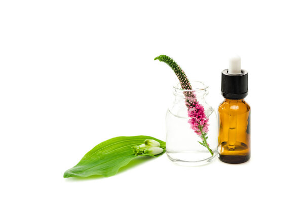 glass bottle with pink veronica flower near green leaf isolated on white 