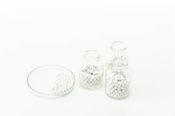 bottles with pills near glass plate isolated on white 