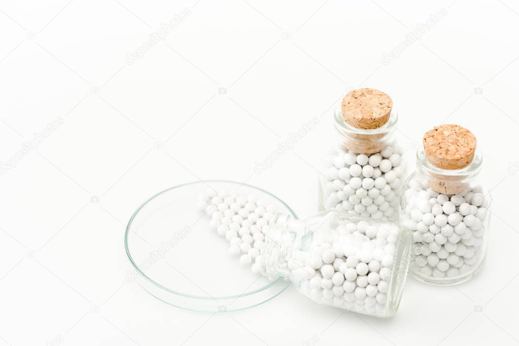 bottle with round small pills near glass petri dish isolated on white 