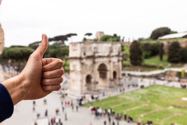 Roma, İtalya - 28 Haziran 2019: Konstantin'in kemerinin önünde başparmağını gösteren adamın kısmi görünümü