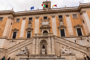 ROME, ITALY - JUNE 28, 2019: bottom view of capitoline museums with sculptures and flags clipart