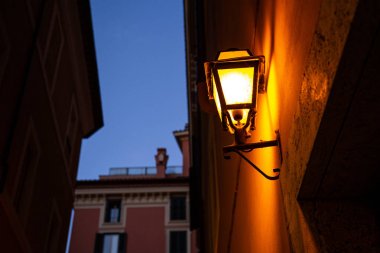 buildings with lighted lantern on wall in evening in rome, italy clipart
