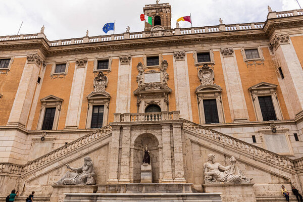 ROME, ITALY - JUNE 28, 2019: bottom view of capitoline museums with sculptures and flags