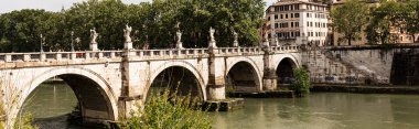Roma, İtalya - 28 Haziran 2019: Tiber Nehri'nin ve güneşli bir günde eski köprüde yürüyen insanların panoramik fotoğrafı