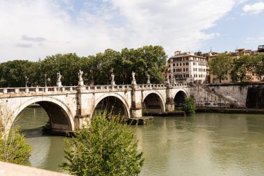 Roma, İtalya - 28 Haziran 2019: Tiber Nehri ve güneşli bir günde bulutlu gökyüzünün altında eski köprüdeki insanlar