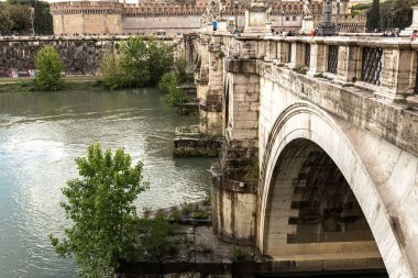 ROME, ITALY - JUNE 28, 2019: river Tiber and people on old bridge under cloudy sky clipart