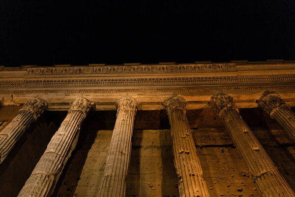 ROME, ITALY - JUNE 28, 2019: bottom view of ancient building with columns at night 
