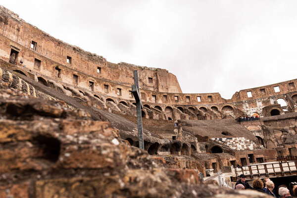 ROME, ITALY - JUNE 28, 2019: ruins of colosseum and crowd of tourists under grey sky