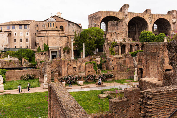 РИМ, ИТАЛИЯ - 28 ИЮНЯ 2019 года: туристы, идущие на римский форум со старинными зданиями
