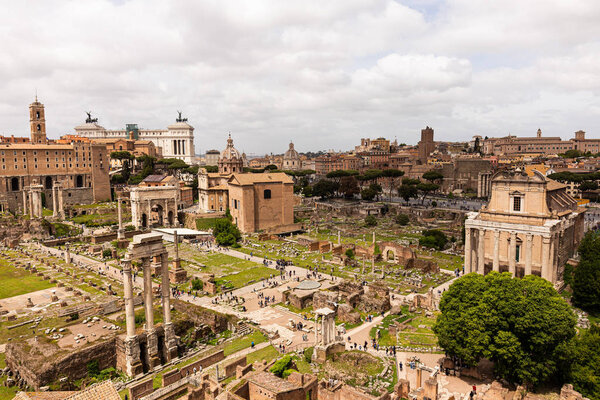 ROME, ITALY - JUNE 28, 2019: tourists walking around roman forum under grey sky