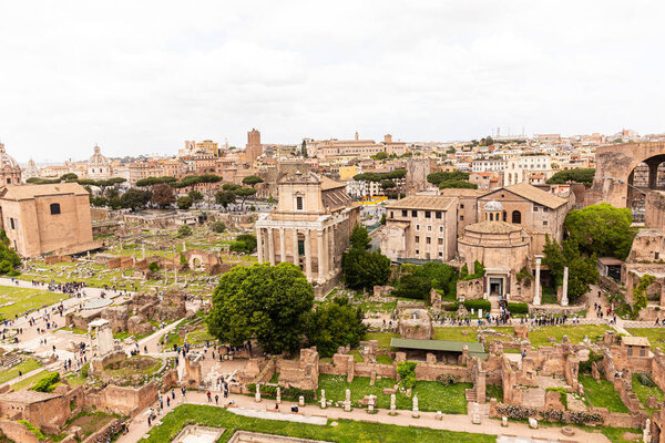 ROME, ITALY - JUNE 28, 2019: tourists walking around roman forum under grey sky