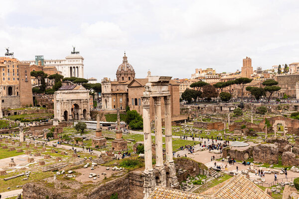 ROME, ITALY - JUNE 28, 2019: tourists walking around roman forum under grey sky