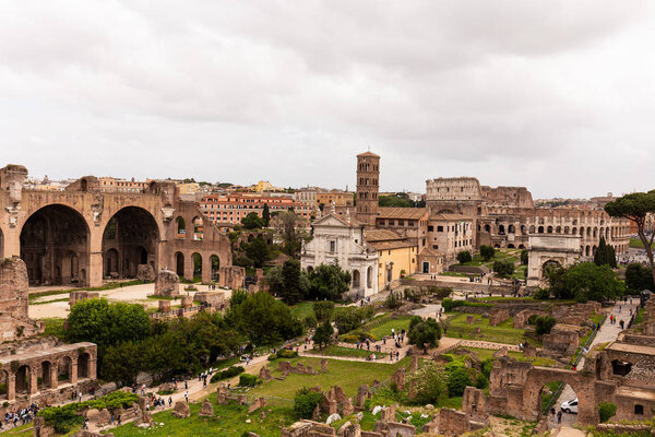 ROME, ITALY - JUNE 28, 2019: tourists walking around roman forum under grey sky