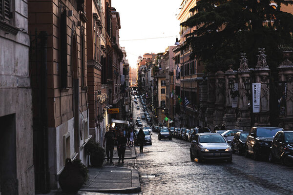 ROME, ITALY - JUNE 28, 2019: people and cars on street near old buildings