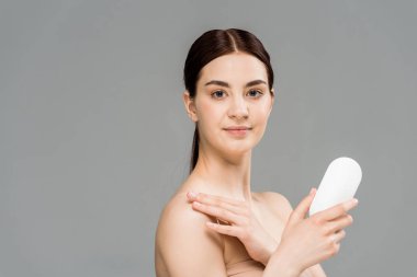 happy young woman holding bottle with body lotion isolated on grey  clipart