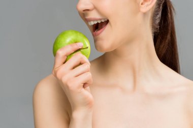 gri izole açık ağız yakınında yeşil elma tutan mutlu kadın kırpılmış görünümü 