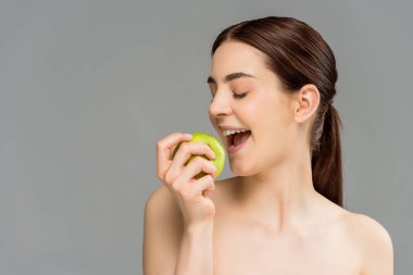  gri izole açık ağız yakınında yeşil elma tutan mutlu kadın 