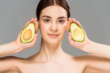 gri izole avokado yarım tutan çekici genç kadın 