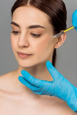 cropped view of plastic surgeon making beauty injection to attractive woman isolated on grey  clipart