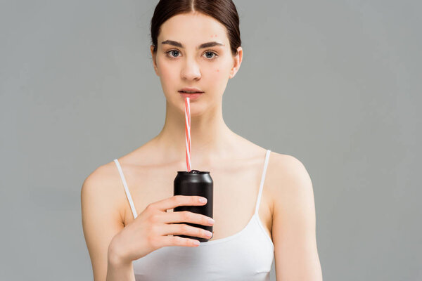 женщина с акне на лице холдинг банка с соломой изолированы на серый
