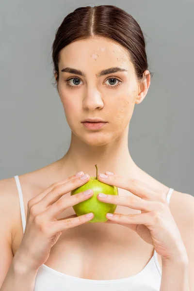 灰色で隔離されたリンゴを保持する皮膚に顔のスクラブを持つブルネットの若い女性 — ストック写真