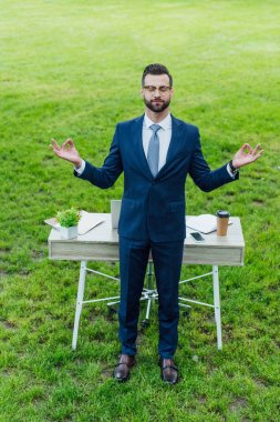 parkta masanın yanında duran meditasyon resmi giyim genç işadamıtam uzunlukta görünümü
