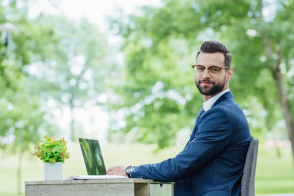 Young Businessman Sitting Table Looking Camera While Using Laptop — Stock Photo, Image