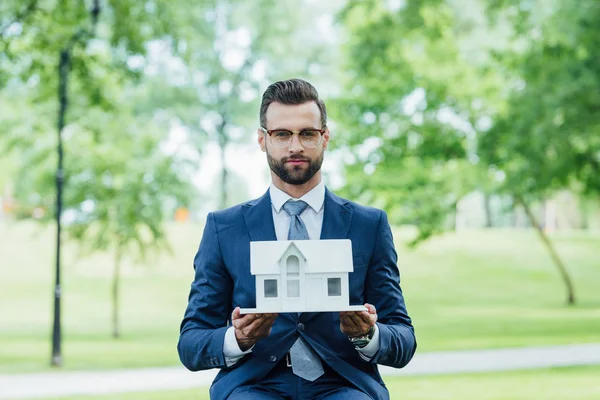 Young Businessman Holding White House Layout Looking Camera While Sitting — Stock Photo, Image