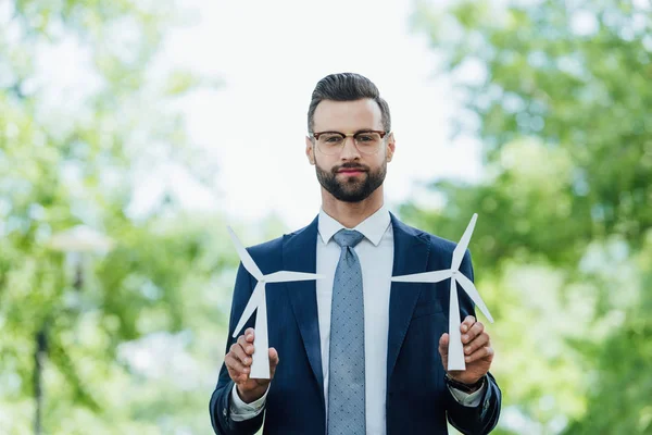 Young Businessman Holding Windmills Layout Looking Camera While Standing Park — Stock Photo, Image