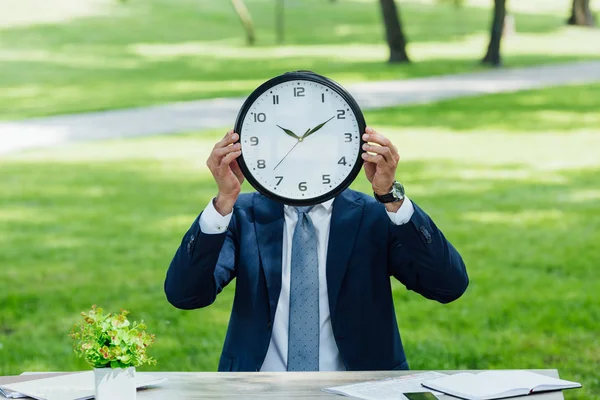 Businessman Sitting Table Plant Notebooks Covering Face Clock — Stock Photo, Image