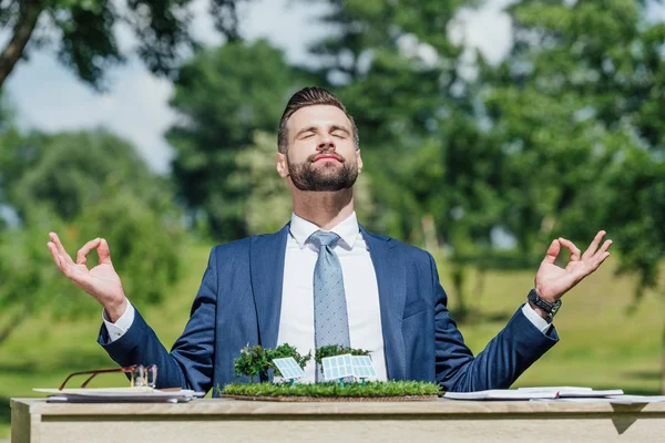 Young Businessman Meditating While Sitting Table Sun Batteries Layout — Stock Photo, Image