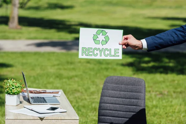 Vista Cortada Empresário Segurando Cartão Com Sinal Reciclagem Perto Mesa — Fotografia de Stock