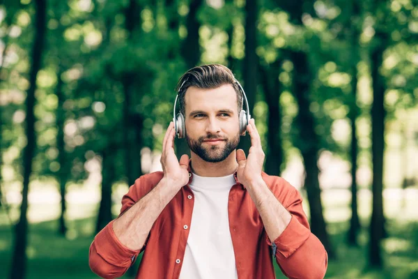 Junger Mann Steht Park Hört Musik Und Schaut Weg — Stockfoto
