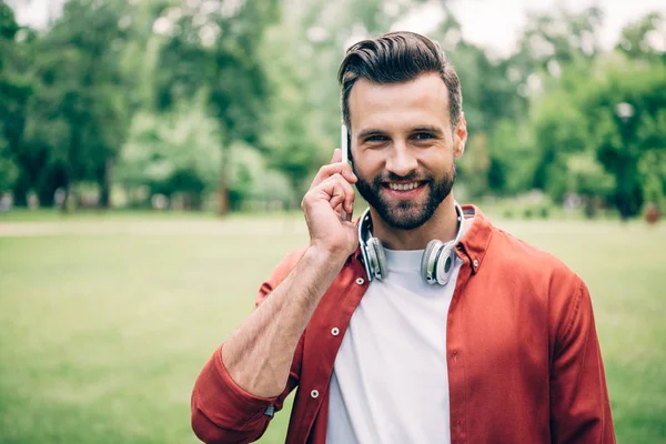 Young Man Standing Park Talking Smartphone Smiling Looking Camera — Stock Photo, Image