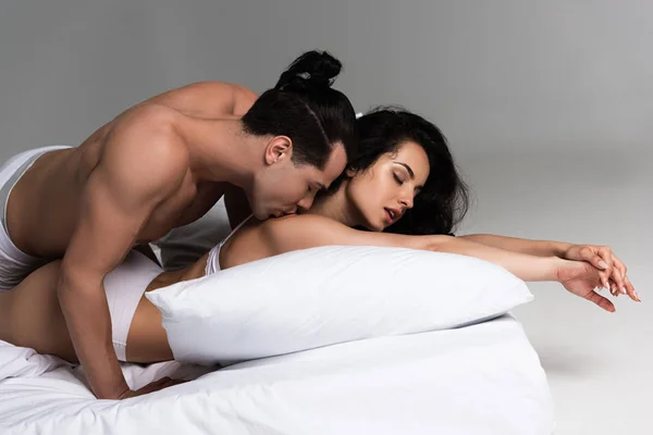 性感的年轻夫妇亲吻 而躺在床上一起 — 图库照片